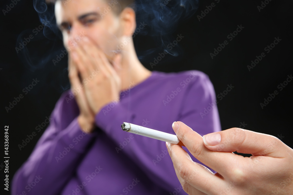 Passive smoking concept. Young man covering face from cigarette smoke