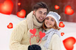 © Africa Studio - Young couple in love holding red paper hearts outdoors in winter