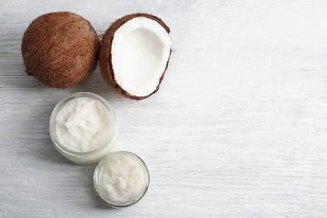 Wall Mural - Jars with fresh coconut oil and nut on wooden background