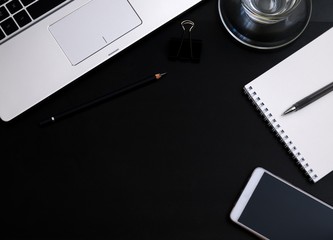 Modern dark office Desk computer, mobile phone,Notepad, pen and Cup. The view from the top