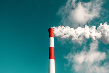 Coal Power Pollution smoking stack. Coal power plant smoking and teaming against a blue and greenish sky.