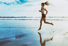 Active Sporty Woman Run Along Ocean Surf By Water Pool To Keep Fit And Health. Sunset Black Sand Beach Background With Sun. Woman Fitness, Jogging Workout And Sport Activity On Summer Family Holiday.