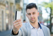 © dobok - young businessman showing credit card on street