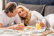© LIGHTFIELD STUDIOS - Happy middle aged couple having breakfast together in bed
