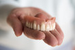 closeup of womans hand holding a teeth denture