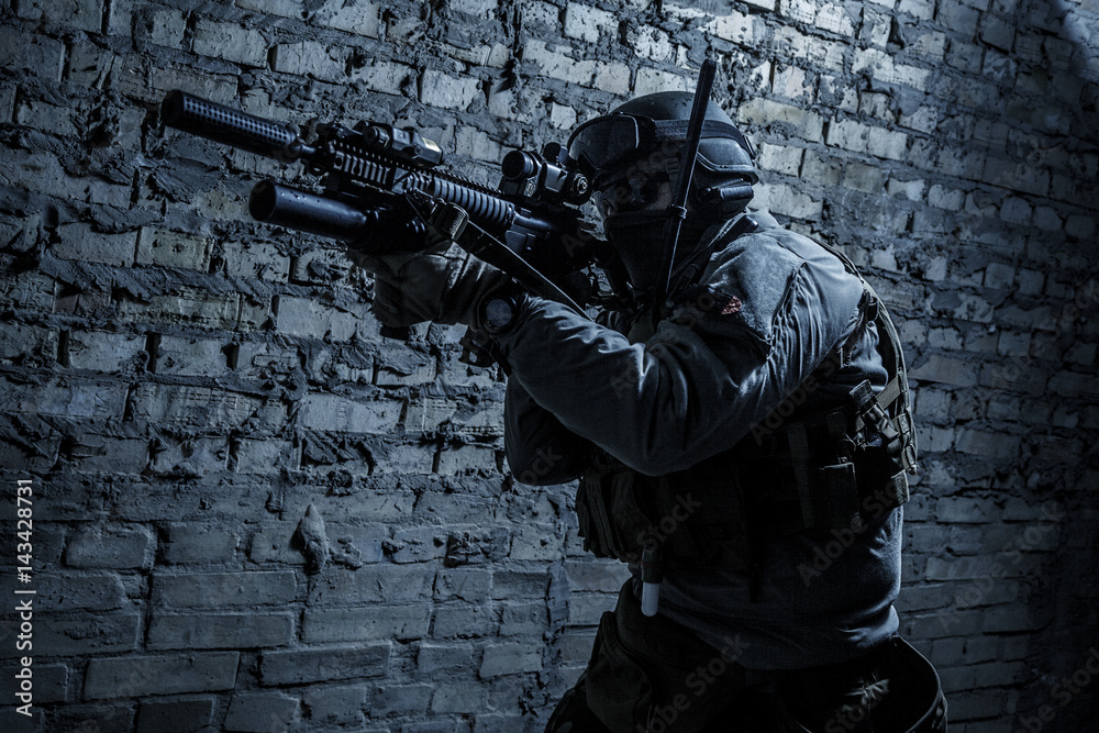 Special forces operator pointing weapon in the dark. Combat helmet ...