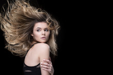 Extremely Gorgeous. Stunning Young Woman Embracing Herself Looking Over Her Shoulder With Her Hair Swept By Wind On Black Background Copyspace On The Side