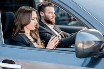 Beautiful business couple driving a car in the city