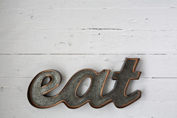 Grey rustic metal eat sign on wooden wall