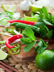 Wall Mural - Vietnamese vegetable ingredients on wooden board, asian cuisine cooking: ginger, lime, chili, garlic, spring onions, chives, shallots, mint and shiitake mushrooms.