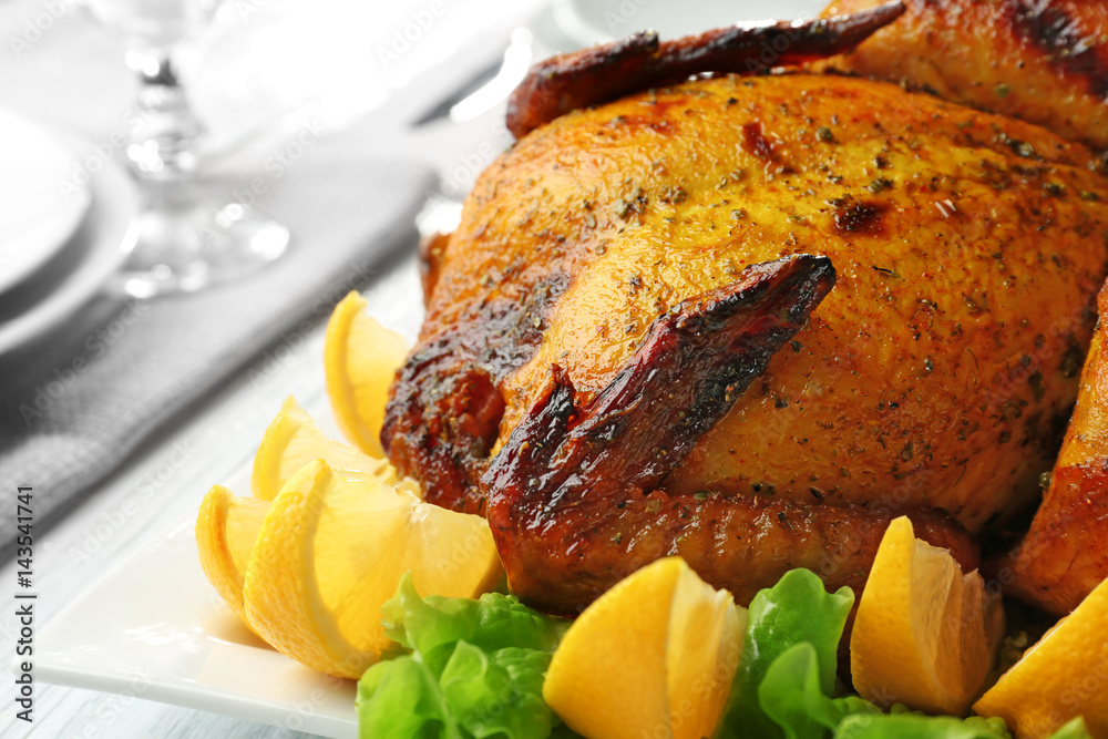 Plate with roasted beer can chicken on table