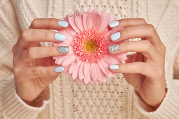 Fotomurales - Pink gerbera with blue manicure.