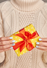 Fotomurales - Beautiful yellow gift with a red bow against a knitted sweater background.