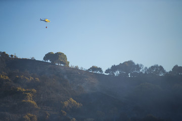 GRANADA, AUGUST 28: Fire fighting Helicopter, with bambi basket, during a fire fighting in the bush. August 28, 2014, Granada, Spain.