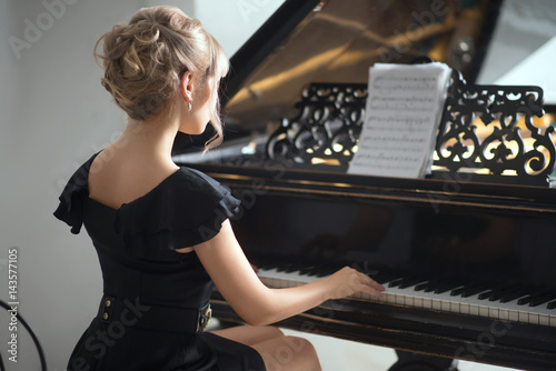 Fotografie, Obraz Portrait of woman in black dress sitting at the piano.