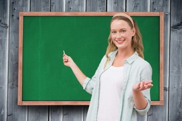 Poster - Portrait of happy female student standing against chalkboard