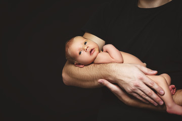 Wall Mural - Newborn baby in his father's hands in dark