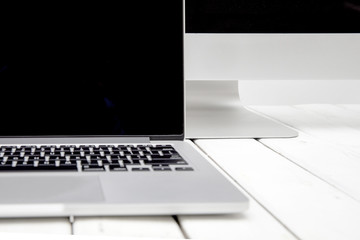 Wall Mural - Laptop with black screen on white wooden table by white background