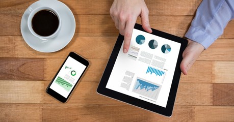 Poster - Businessman analyzing graphs on digital tablet at wooden desk