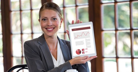 Poster - Portrait of happy businesswoman showing graphs on digital tablet
