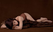 Woman in Lacy Brown Bodysuit Lying on Fur Blanket