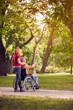 © luckybusiness - family time- senior man in wheelchair and daughter in the park.
