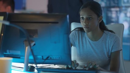  Young creative computer game designer working with colleagues in dark office. 