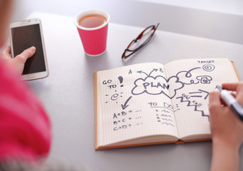 Wall Mural - Young woman writes to diary on a white table