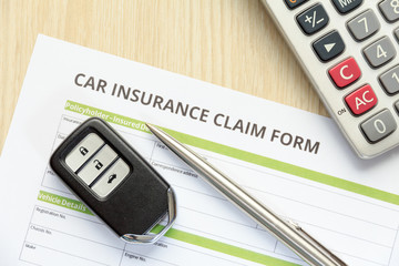 Wall Mural - Top view of car insurance claim form with car key and calculator on wooden desk.