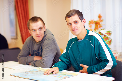 Fotografía cheerful adult men with disability sitting at the desk in rehabilitation center