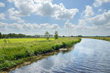 
Canalised River And Cloudy Sky In A Dutch Landscape In The Province Of Drenthe, The Netherlands. 