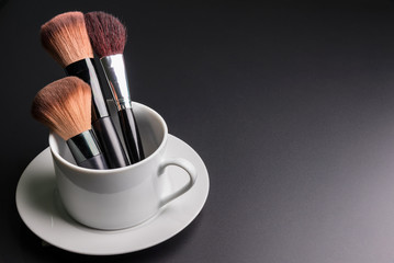 Set of flat top view of various professional female cosmetics brushes for makeup in white coffee cup 