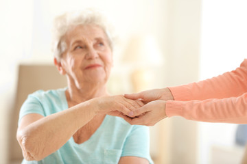 Wall Mural - Old and young women holding hands on blurred background, closeup