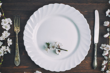 Wall Mural - White plate with a fork and knife on a brown wooden surface