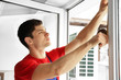 © Africa Studio - Young worker applying rubber strip onto window in office