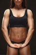 © Nestor - Focused on result. Cropped studio shot of a fit female athlete stretching her hands on black background.