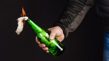 Glass Bottle, The So-called Molotov Cocktail In The Hand Of The Activist. Isolated On A Black Background.