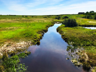  Rural prairie landscape with a boggy creek running through marsh land in summer.