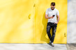 © rh2010 - Colorful portrait of a handsome man dressed in white t-shirt and jeans with phone on the yellow background