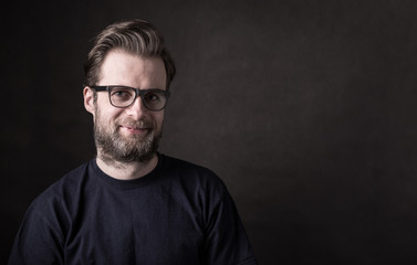 Dark moody portrait of happy caucasian man in glasses