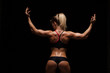 © satyrenko - Beautiful athletic woman in sporty cloths is posing, holding hands up and showing her perfect body, back view isolated on dark background with copyspace