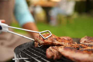 Poster - Preparing of steaks on barbecue grill in garden, close up view