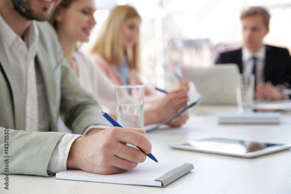 Man making notes in notebook at business presentation