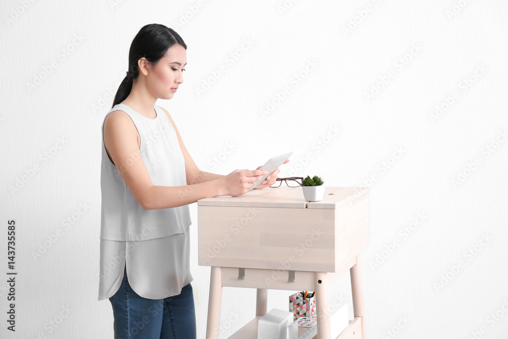 Asian woman with tablet computer at stand-up workplace