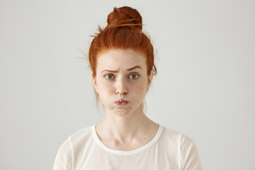 Annoyed irritated young red-haired female with freckles blowing her cheeks, frowning, feeling frustrated with something. Human facial expressions, emotions and feelings. Fatigue or boredom concept