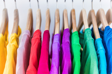 fashion clothes on clothing rack - bright colorful closet. closeup of rainbow color choice of trendy