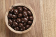 © GCapture - chocolate covered almonds in wood bowl on table, with copy space