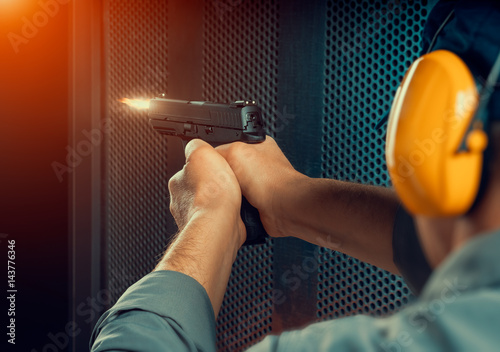 Papel de parede man firing pistol at target indoor shooting range