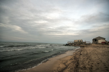 Beautiful surreal landscape of abandoned house and ladder on rocky seashore at sunset time. Cloudy weather. Caspian Sea, Azerbaijan,