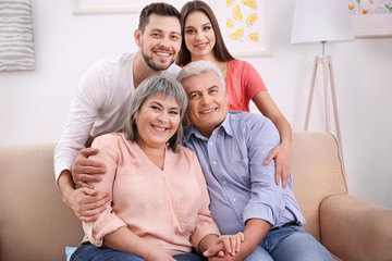 Young couple with middle aged parents on sofa in the room